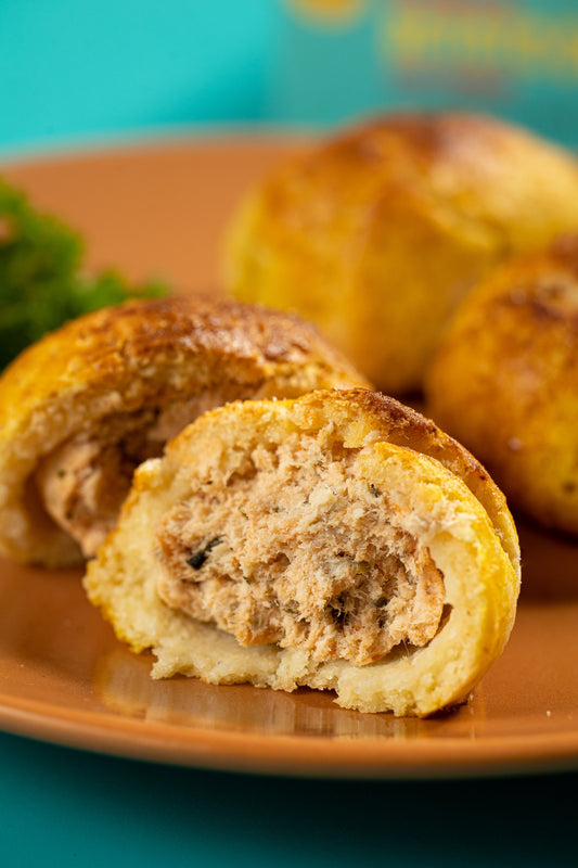 Pãozinho de batata doce partido, em close, mostrando o recheio de frango desfiado