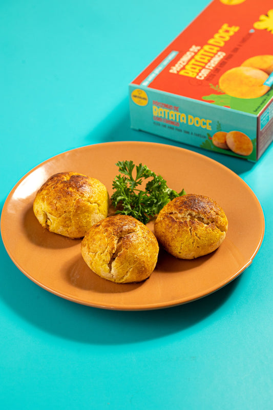 Quatro pãezinhos de batata doce com frango em prato laranja sobre fundo turquesa